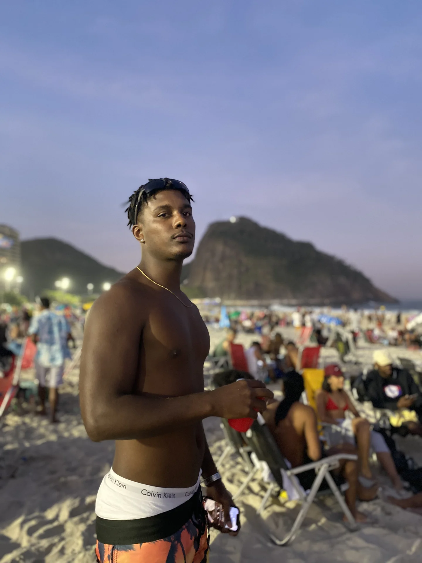 Ondas chegando a uma praia do Rio à noite com as luzes da cidade ao fundo